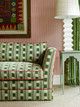 Lost and found green sofa with vertelli rosa piping with a side table and lamp and striped wall in background. Photography by Christopher Horwood at Ham Yard Hotel